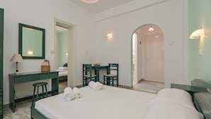Une chambre d’hôtel comprenant un lit, un bureau, une chaise, un miroir et une petite table avec un panier.