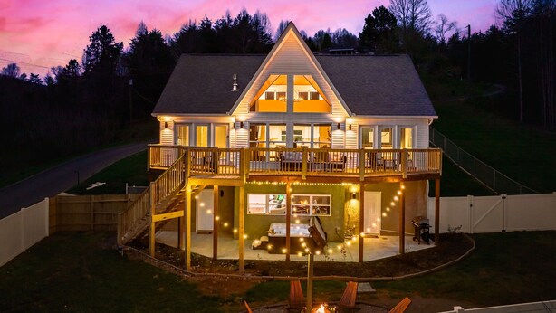 Ein zweigeschossiges Haus mit Balkon, Terrasse und Feuerstelle im Garten.