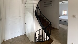 A modern interior with a wooden staircase, a white door, and a ceiling fan.