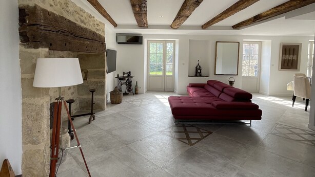 A spacious living room with exposed wooden beams, a red sofa, a lamp, and a sewing machine.