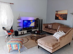 A living room with a television, sofa, ottoman, and coffee table.