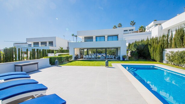A modern villa with a swimming pool, outdoor seating, and a well-maintained garden.