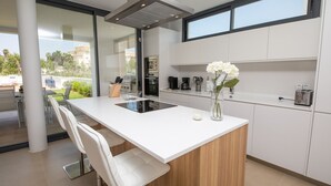 A modern kitchen with a central island, white cabinetry, and a view of the outdoors.