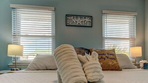 A neatly made bed with a pillow labeled "Candy Toes Salty Kisses" and a decorative wall piece. - It’s a SHORE THING-Modern finishes! Short walk to the soft beaches on the Gulf (Indian Shores)