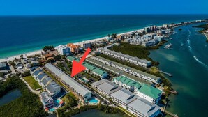 An aerial view of a coastal hotel area with multiple buildings, a marina, and a beach. - It’s a SHORE THING-Modern finishes! Short walk to the soft beaches on the Gulf (Indian Shores)