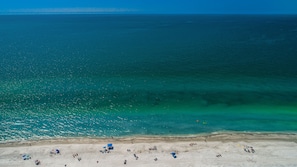 A beach with clear turquoise water, sandy shore, and people sunbathing. - It’s a SHORE THING-Modern finishes! Short walk to the soft beaches on the Gulf (Indian Shores)