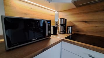 A modern kitchen with a built-in microwave, coffee maker, and a coffee pot on a wooden countertop.