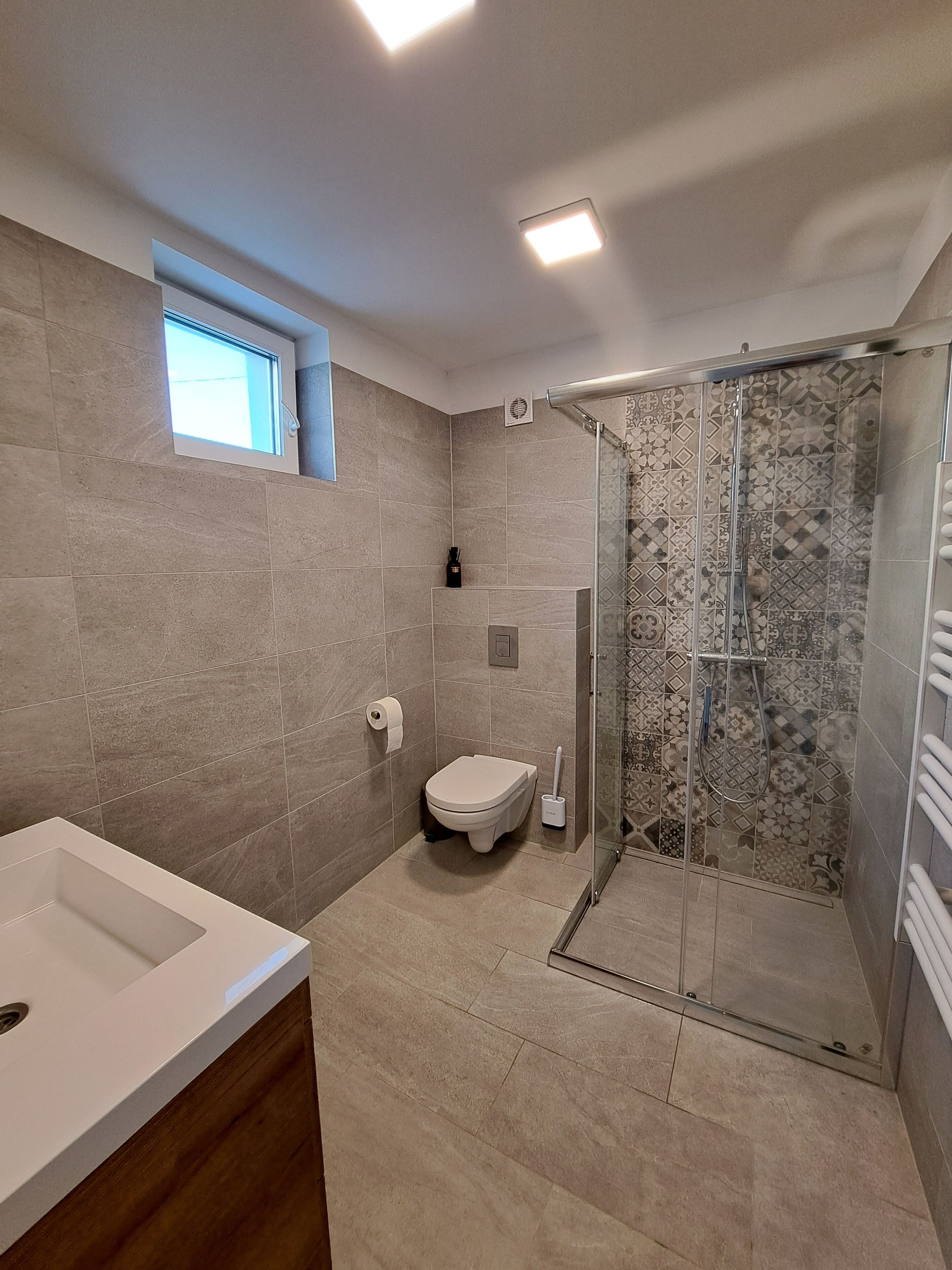 A modern bathroom with a shower, toilet, and sink.