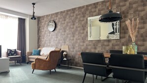 A modern living room with a sofa, armchair, dining table, and chairs.