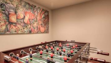 Une table de baby-foot dans une pièce où est accrochée une grande peinture abstraite au mur.