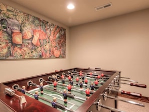 A foosball table in a room with a large abstract painting on the wall.