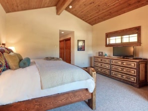 A bedroom with a wooden bed, a dresser, and a television.
