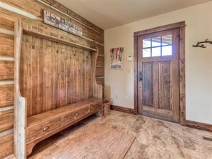 A room with a wooden bench, a door, and a wall with a 'Fly Fishing' sign. - Luxury 5 Bedroom Big Sky Retreat (Big Sky)