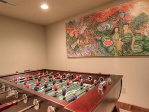 Una mesa de fútbolín en una habitación con un mural grande y colorido en la pared.