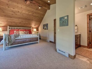 Une pièce chaleureuse avec un plafond en pente, un banc recouvert d’une couverture et une petite table avec une lampe.
