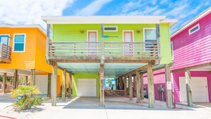 A colorful building with a balcony, a garage, and a covered walkway. - Mermaid Cove PA! Beach Gear Credit, Community Pool (Port Aransas)