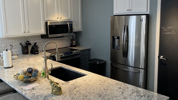 A modern kitchen with white cabinets, stainless steel appliances, and a granite countertop. - Luxury 3bd/2ba Beach Condo on Golf Course (Myrtle Beach)