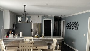 A spacious kitchen with modern appliances, a dining area with wooden furniture, and a dark wood floor. - Luxury 3bd/2ba Beach Condo on Golf Course (Myrtle Beach)