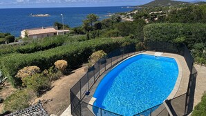 Piscina com vista para o mar e colinas.
