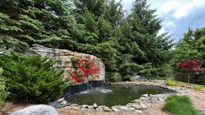 A pond with a waterfall, surrounded by dense greenery and a large rock with the text "Sullivan". - Mountain top spacious townhome in 7 Springs Southwind (Champion)