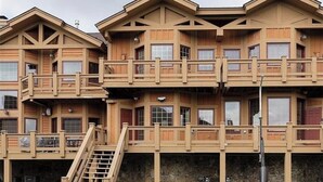 A multi-story wooden building with balconies, a staircase, and a stone foundation. - Mountain top spacious townhome in 7 Springs Southwind (Champion)