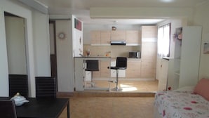 A compact room with a dining table and chairs, a kitchenette with a microwave, and a bed with a floral bedspread. - House with pool in Le Pradet quiet location  (Le Pradet)