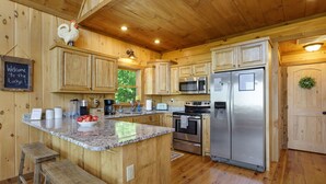 A wooden cabin kitchen with granite countertops, stainless steel appliances, and a welcome sign. - Cascading View Lodge♡ Mtn Views, hot tub, fire pit, < 20 min from Blue Ridge (Blue Ridge)