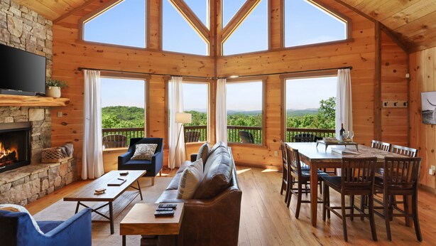 A spacious wooden cabin with a stone fireplace, a large TV, and a dining area with a view of the mountains. - Cascading View Lodge♡ Mtn Views, hot tub, fire pit, < 20 min from Blue Ridge (Blue Ridge)