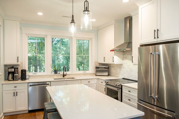 A modern kitchen with white cabinetry, stainless steel appliances, and a large island.