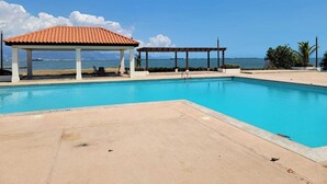 A swimming pool with a covered area and a view of the sea. - Bayfront Villas and Apt (Portmore)