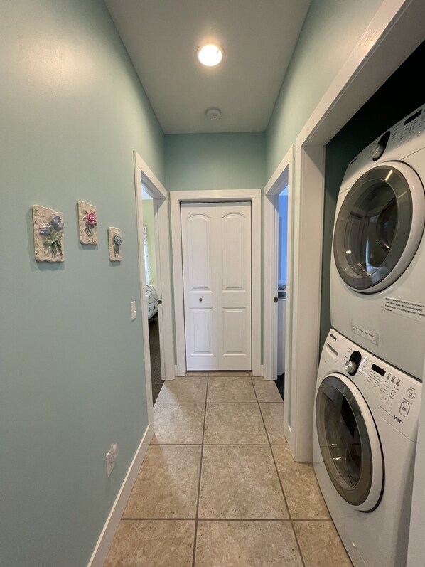A laundry room with a washing machine and dryer, a door, and a light fixture. - Beautiful, well maintained home on Lake Michigan at Indian Point! (Beaver Island)