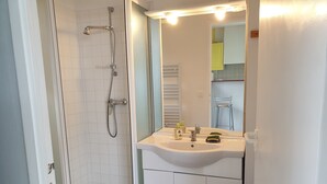 Een badkamer met douche, wastafel en spiegel.