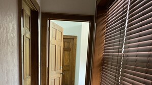 A narrow hallway with wooden doors and a window with blinds. - Coal Town Gem (Haysi)