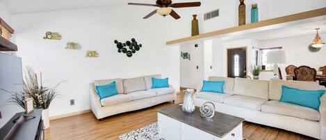 A living room with two sofas, a coffee table, and a ceiling fan.