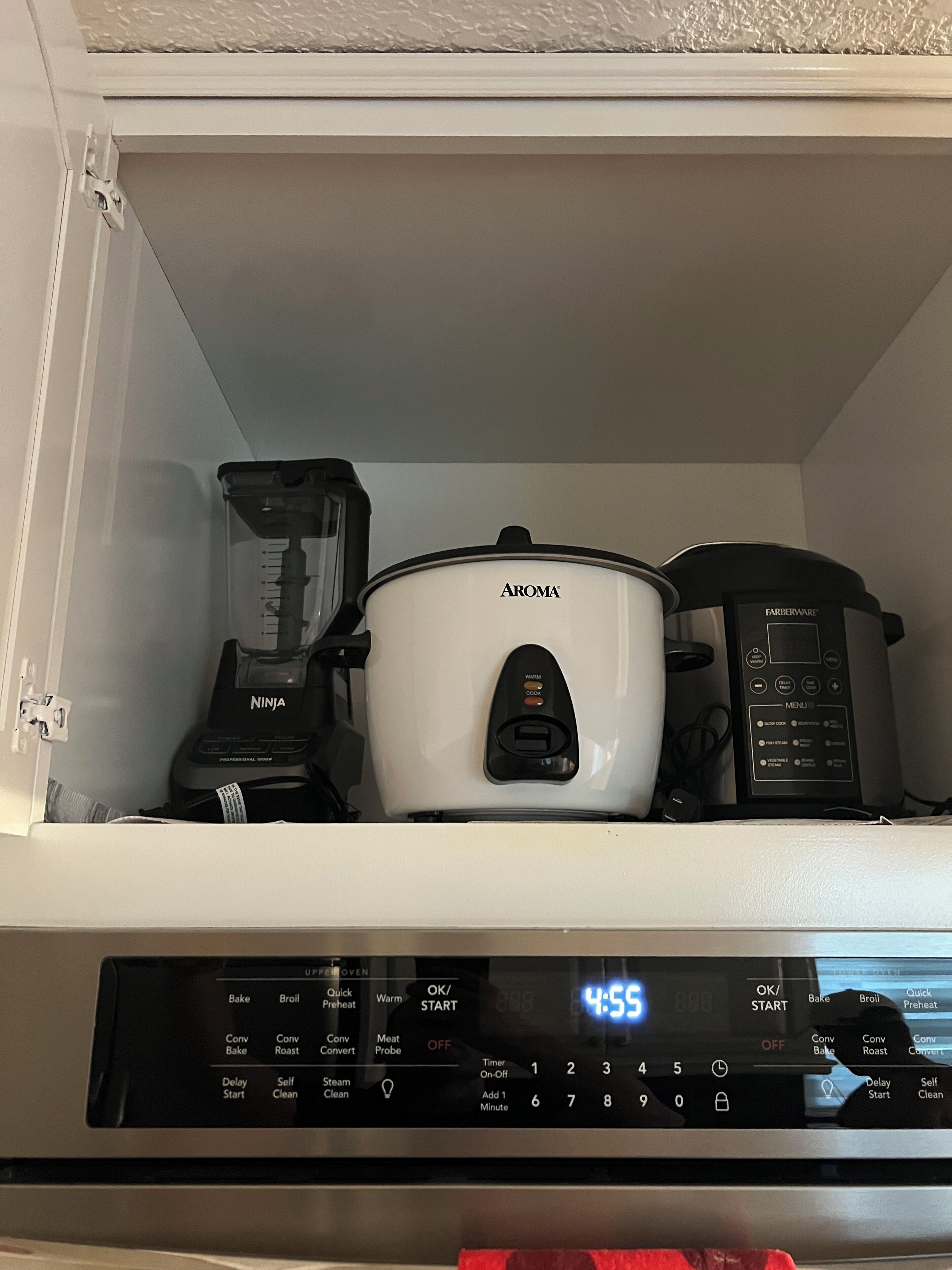 Et køkken med en hvid slow cooker mærket "AROMA" og en sort food processor på bordet.
