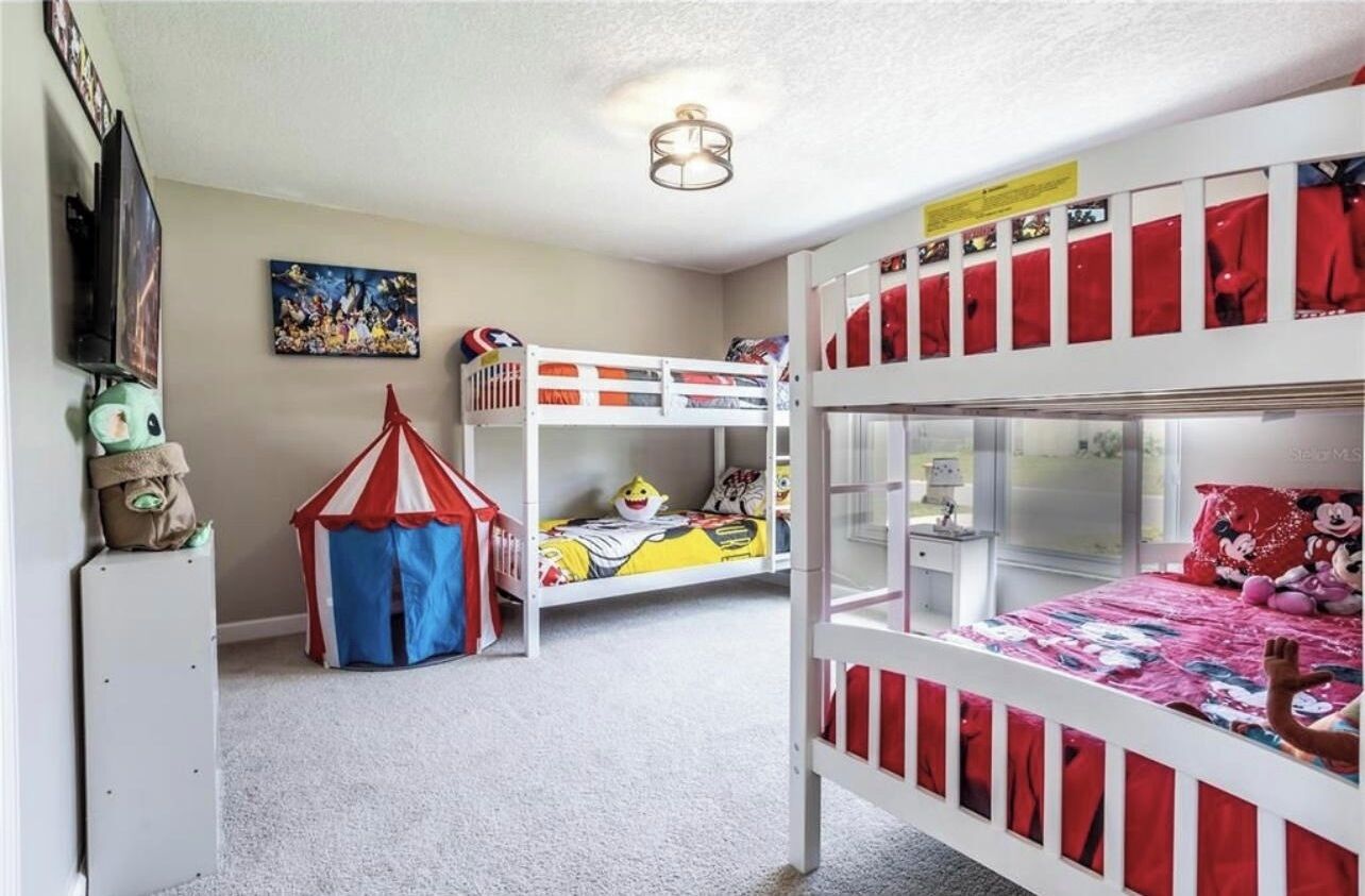 A child's bedroom with bunk beds, a play tent, and a wall-mounted TV.