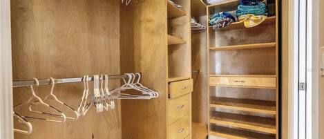 A wooden closet with hanging space and drawers.
