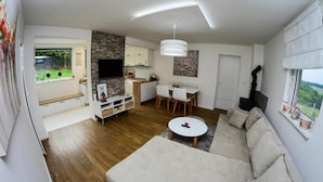 A modern living room with a sofa, a coffee table, a TV, and a dining area with chairs and a table.