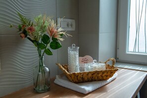 A bathroom vanity with a vase of flowers, a glass jar, and a basket containing toiletries. - Linda- two bedroom apartment - Zadar center (Zadar)
