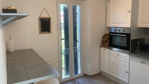 A compact kitchen with white cabinets, a built-in oven, and a small countertop. - Ideal Holiday Home for the 2024 Olympics Games in Marseille: Comfort & Proximity (Marseille)