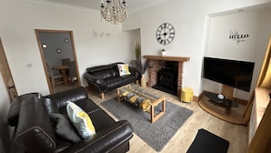 A living room with a fireplace, a television, and a chandelier.