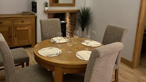 A dining area with a round wooden table, six grey upholstered chairs, and a large mirror above the table.