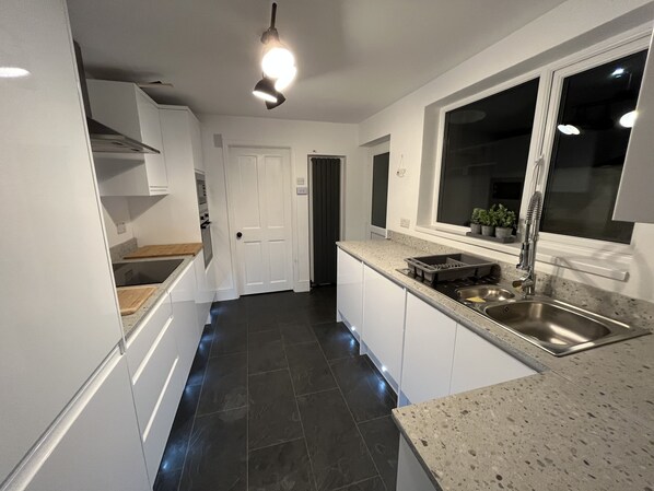 A modern kitchen with white cabinets, a granite countertop, a stainless steel sink, and a window with a view.