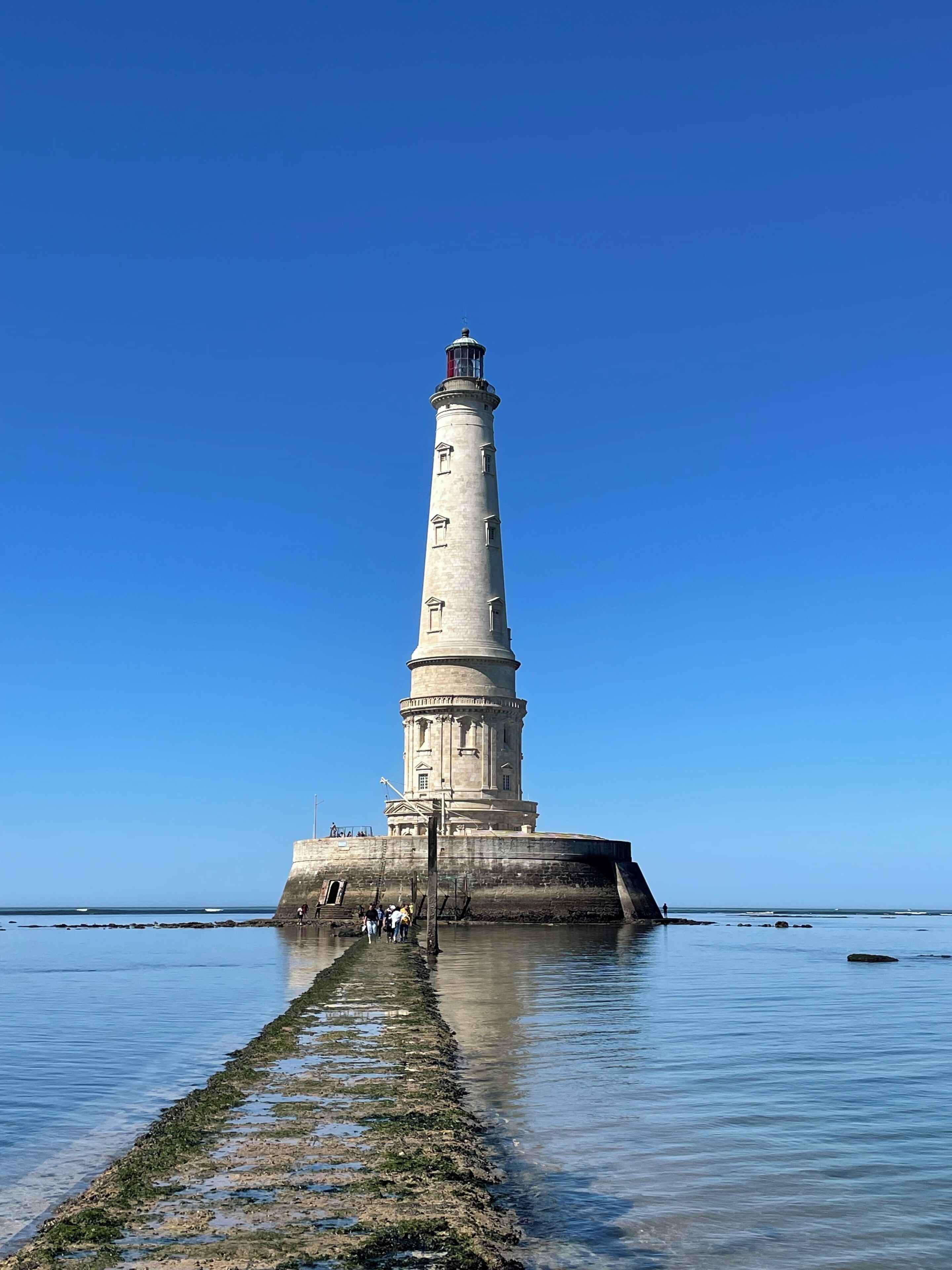 A lighthouse on a small island with a clear sky.