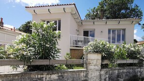 A two-story house with a balcony, a small garden, and a white fence. - Renovated house with garden - 3 min walk from Le Bureau and Nauzan beaches (Saint-Palais-sur-Mer)