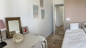 A bedroom with two single beds, a bedside table, a chair, and a wall-mounted lamp. - Renovated house with garden - 3 min walk from Le Bureau and Nauzan beaches (Saint-Palais-sur-Mer)