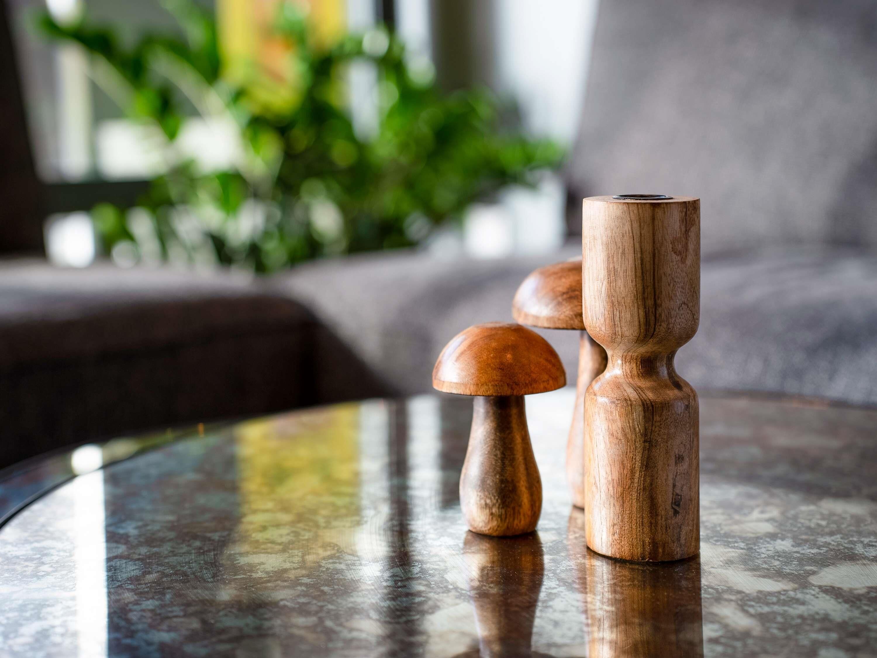 A round table with a reflective surface, a wooden object resembling a mushroom, and a cylindrical wooden item.