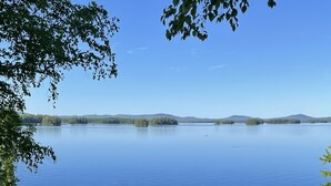 A lakeside cabin with a dock, surrounded by lush greenery and clear blue water. - Private Lakefront Gem Within Minutes of Baxter State Park (Millinocket)
