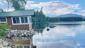 A lakeside cabin with a dock, a kayak, and a calm lake. - Private Lakefront Gem Within Minutes of Baxter State Park (Millinocket)