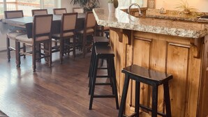 A spacious kitchen with wooden cabinets, a granite countertop, and bar stools.